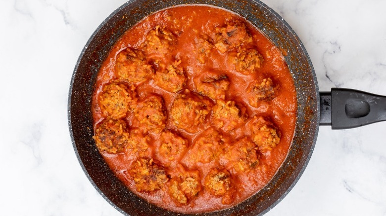 Fully cooked porcupine meatballs and sauce in a skillet.