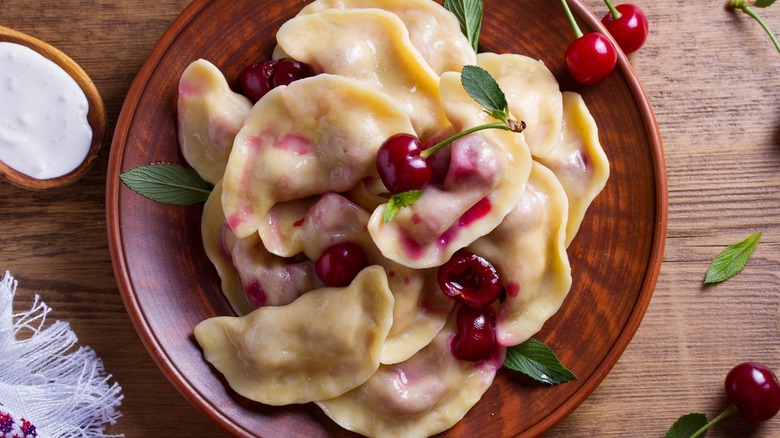 Sweet pierogi with cherries on wooden plate