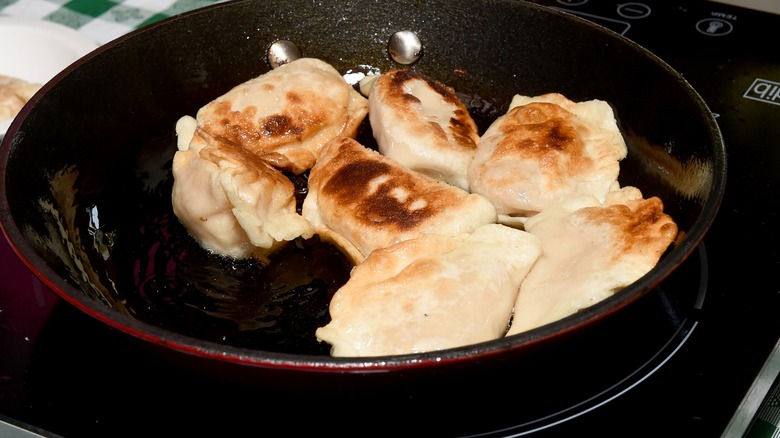 Seven pierogi frying in a pan