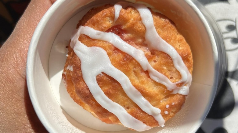 person holding Popeyes strawberry biscuit