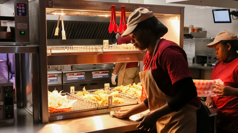 Two Popeyes employees working at the grill