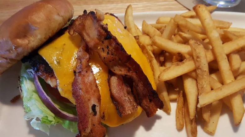 bacon cheddar grilled chicken sandwich with strips of bacon, melted cheddar cheese, grilled chicken, brioche buns, and served alongside seasoned fries