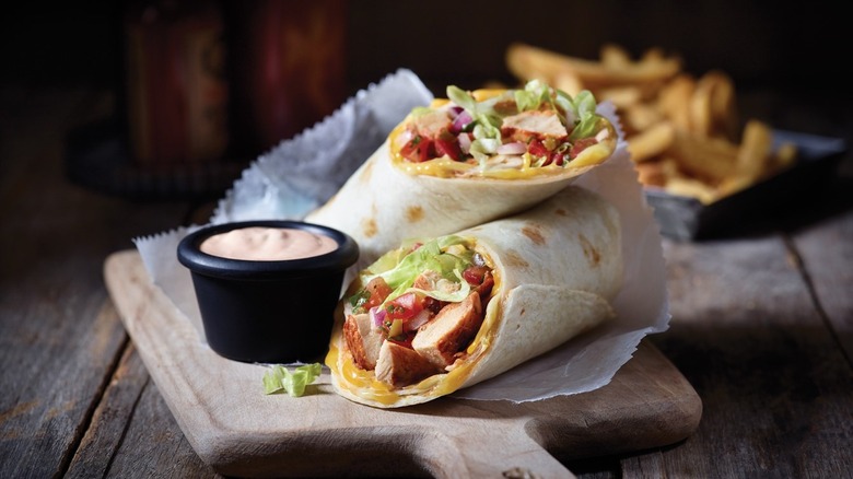 chicken fajita rollup with dipping sauce and seasoned fries on a green and white plate