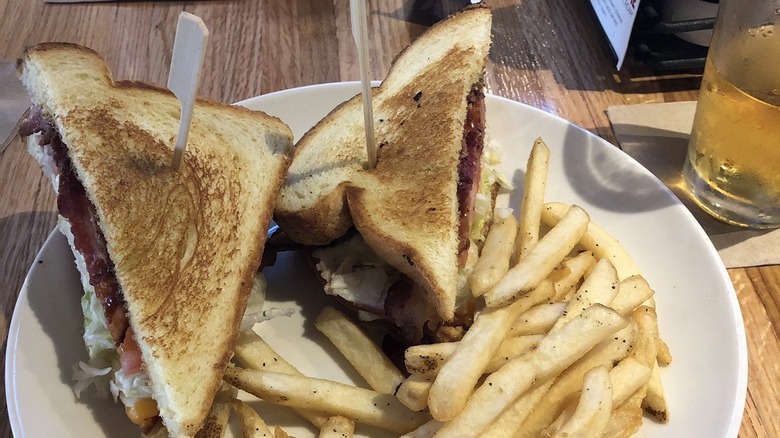 clubhouse grille sandwich with ham, turkey, cheese, bacon, tomato, lettuce, crisp bread, and seasoned fries