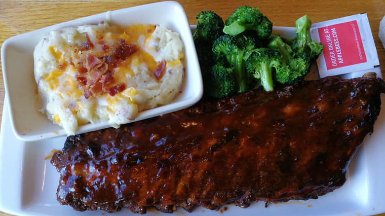 white plate of double-glazed baby back ribs with a side of steamed broccoli and mashed potatoes with bacon and cheese