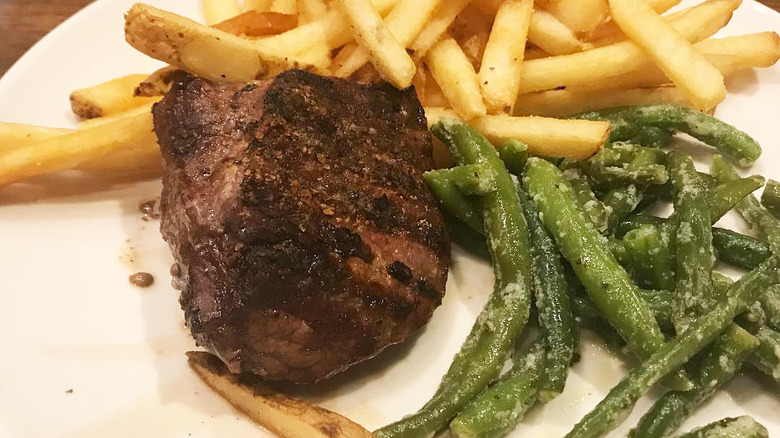 white plate of sirloin, garlicky green beans, and seasoned fries from Applebee's