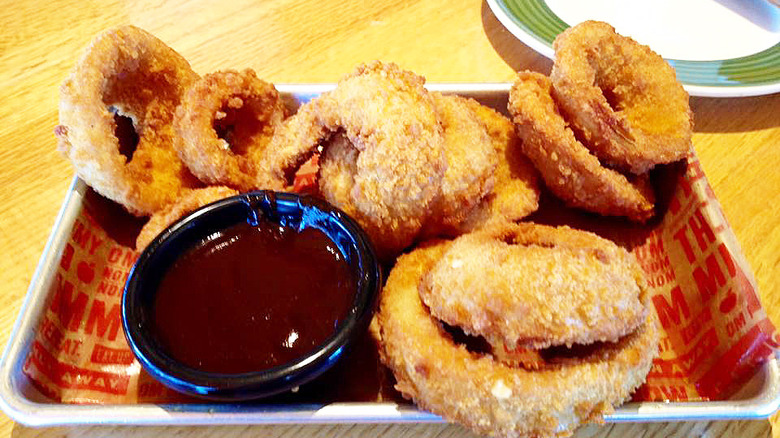 metal tray with Applebee's onion rings and a cup of dipping sauce on a wooden table