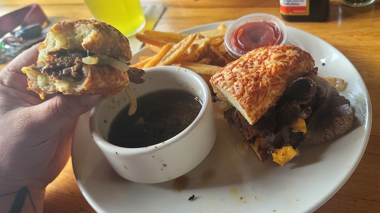 Person eating Applebee's prime rib dipper sandwich