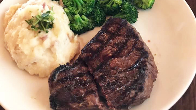 sirloin steak with steamed broccoli and mashed potatoes on a white plate
