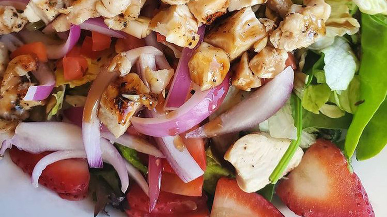 chunks of grilled chicken mixed with fresh greens, red onions, strawberries, tomatoes, almonds, and more with a balsamic dressing