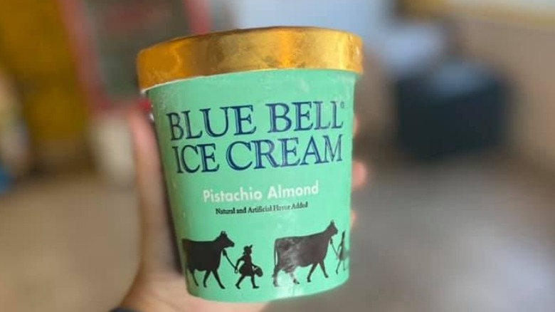 Person Holding Container of Blue Bell Pistachio Almond Ice Cream