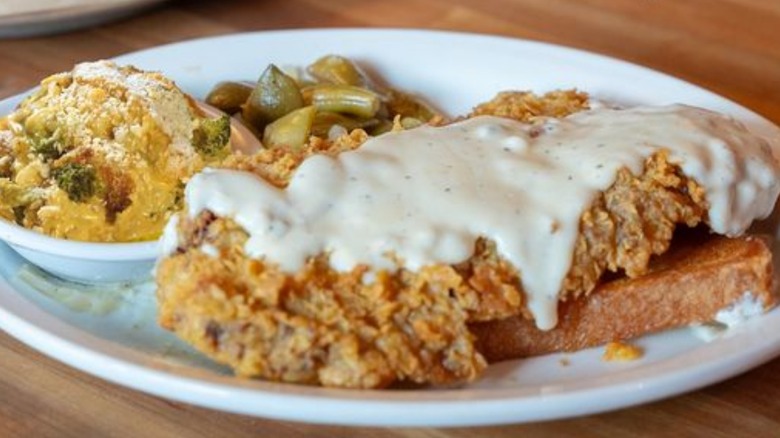 Cheddar's country fried steak is covered in gravy and served with two sides.