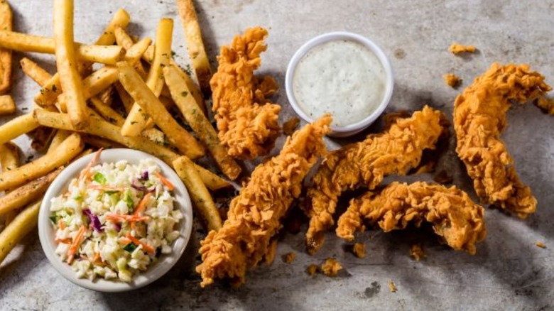 Cheddar's chicken tenders spread out with fries and a bowl of coleslaw.