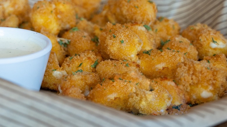 Wisconsin Cheese Bites are shown on paper with a side of ranch dipping sauce.