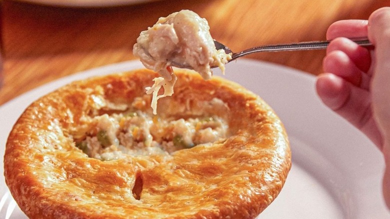 A person holds a spoonful of Cheddar's chicken pot pie.