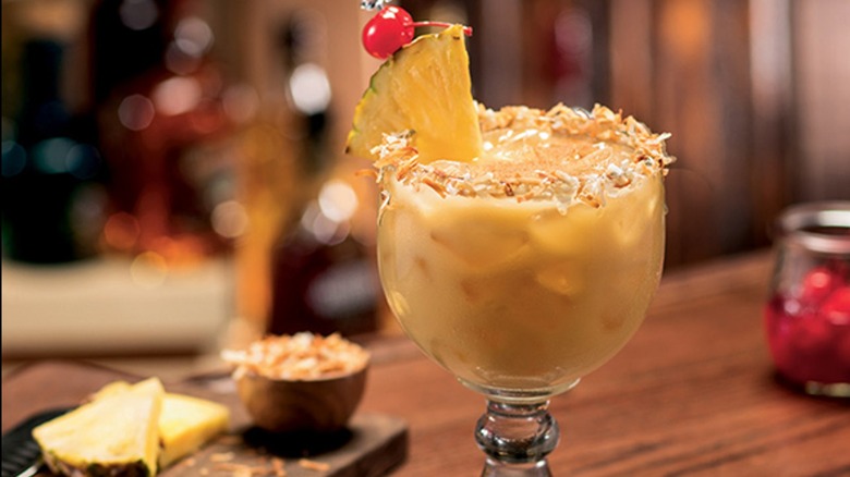 A Cheddar's painkiller cocktail is garnished with a slice of pineapple and a maraschino cherry.