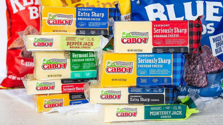 A stack of cabot cheeses in front of bags of chips