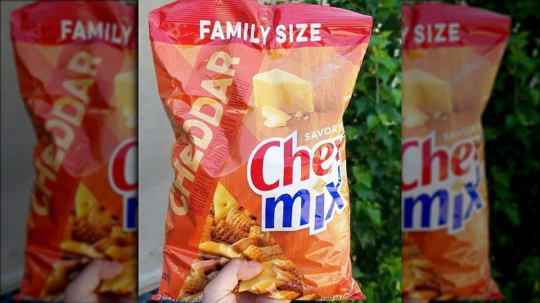 Someone Holding a Bag of Chex Mix Cheddar Flavor