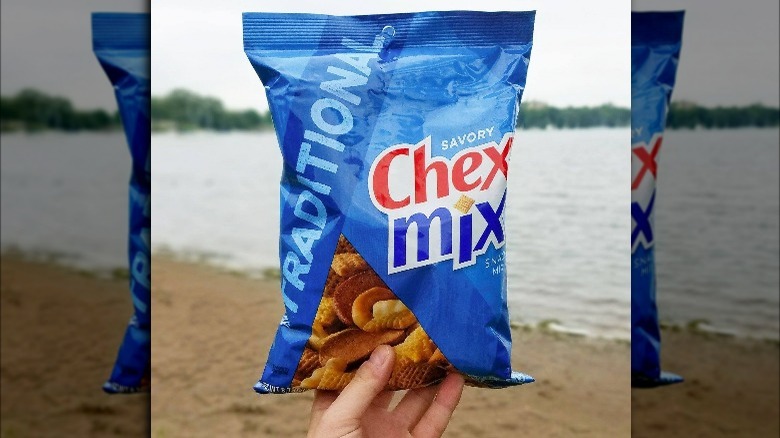 Someone Holding Bag of Traditional Chex Mix at the Lake