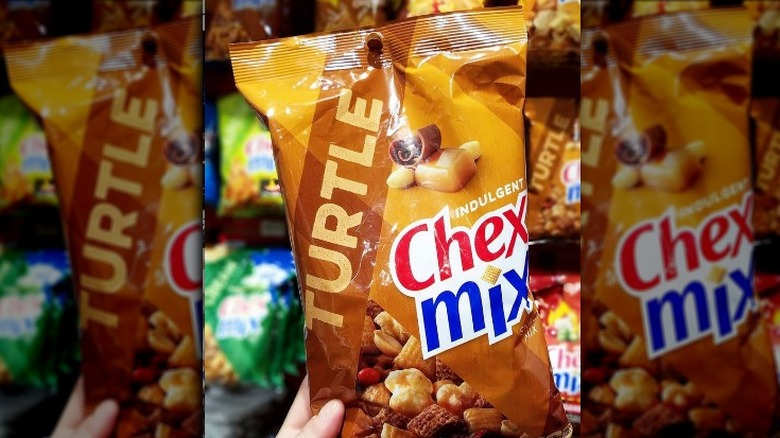 Someone Holding Bag of Turtle Chex Mix in the Store