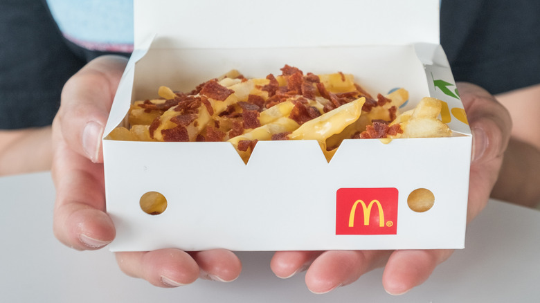 hands holding box of McDonald's cheesy bacon fries