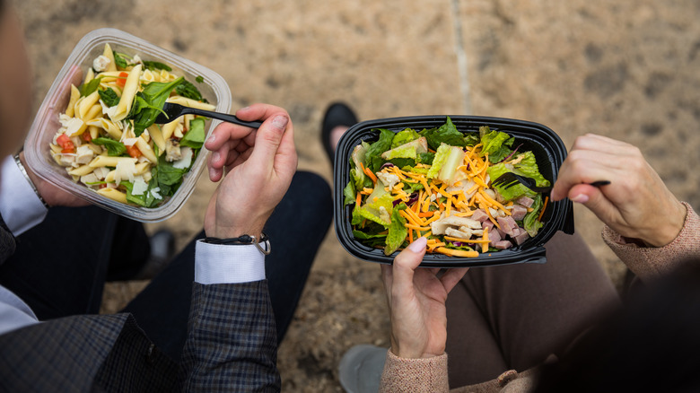 two people holding salads