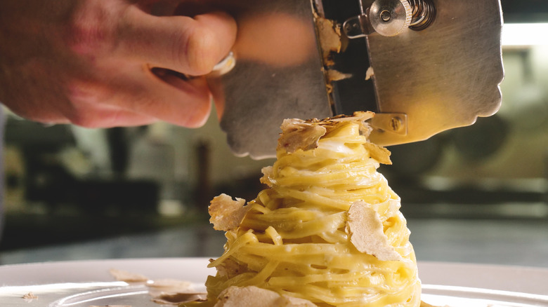 chef shaving truffles onto pasta 