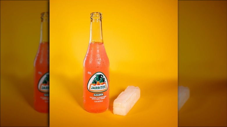 A bottle of guava jarritos beside a block of sugar