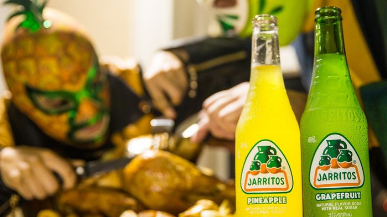 two bottles of jarritos in front of two luchadors eating a turkey