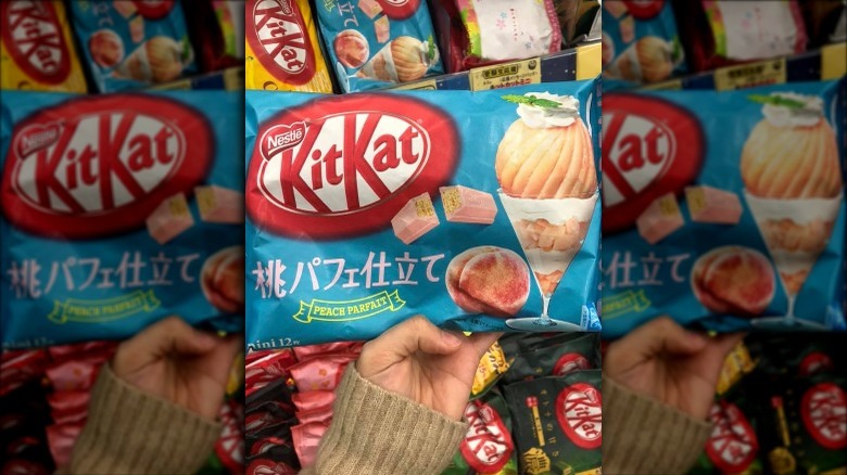 Someone holding Peach Parfait flavor Kit Kat package in store