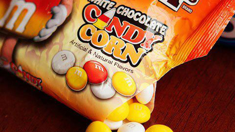 bag of white chocolate candy corn M&Ms on a wooden table 