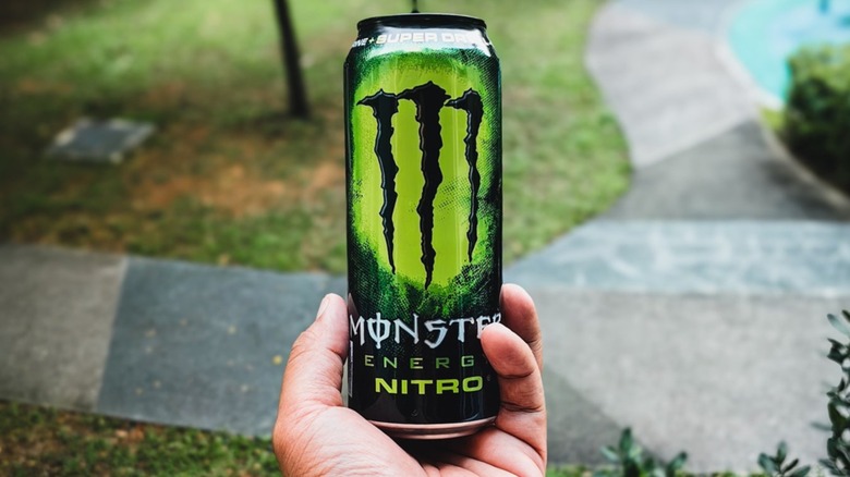 A hand holding Monster Nitro Super Dry