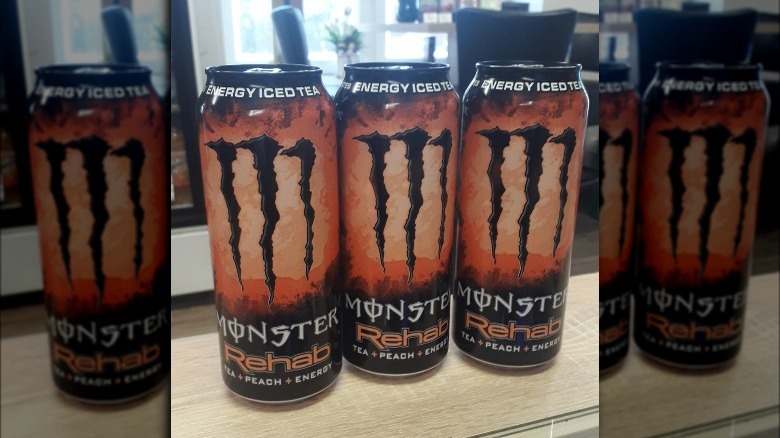 Three cans of Peach Tea Monster Rehab on counter