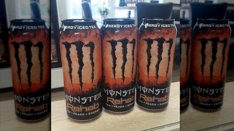 Three cans of Peach Tea Monster Rehab on counter