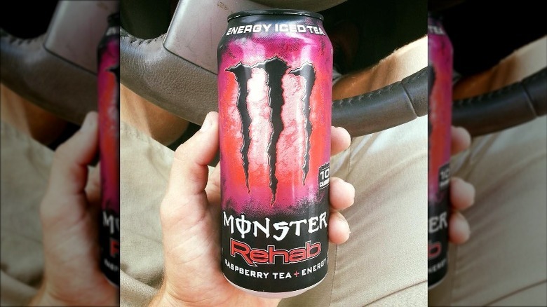 Someone holding Raspberry Tea Monster Rehab can in car