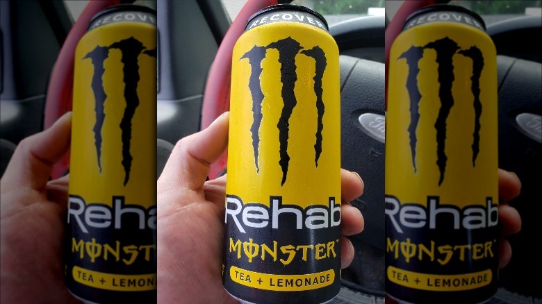 Someone holding a can of Tea & Lemonade Monster Rehab in car
