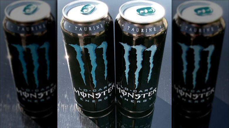 Cans of The Original Lo-Carb Monster Energy drink on black counter