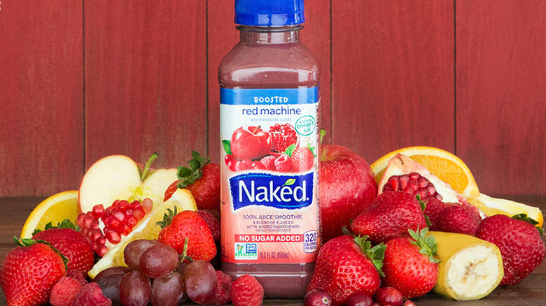 A bottle of red machine smoothie sitting in a pile of fruit and berries