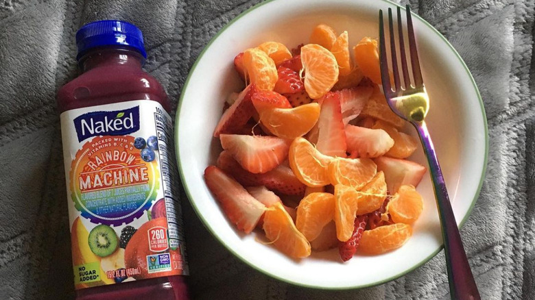 A Bottle of Naked Rainbow Machine smootie next to a bowl of fruit with a fork