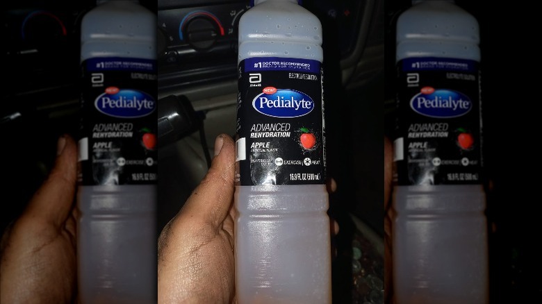 Someone holding half liter bottle of Apple Pedialyte