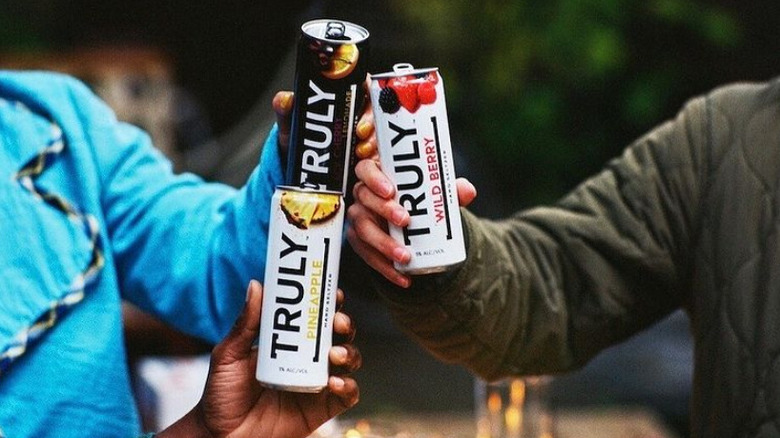 hands cheersing with cans of Truly