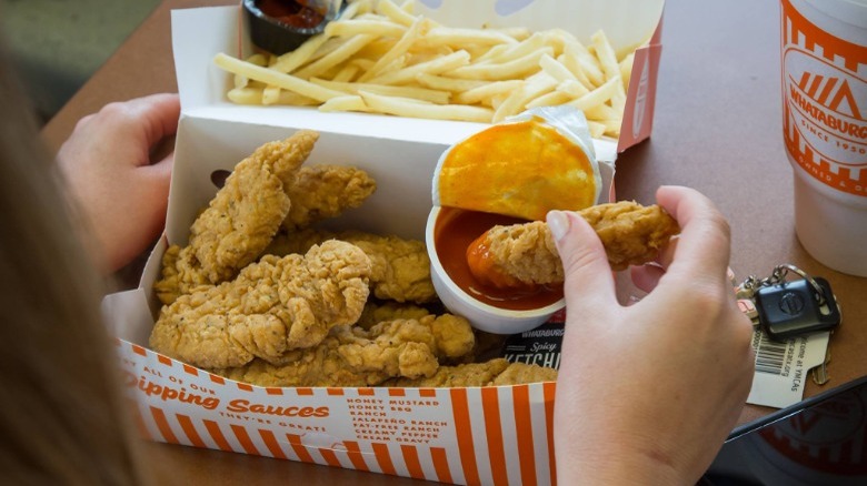 Person dipping Whataburger Whatachick'n Strips in sauce