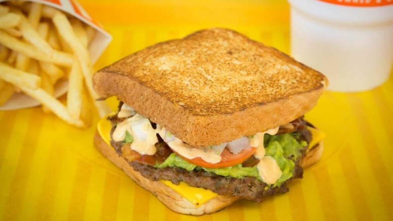 Whataburger Avocado Bacon Burger, fries and drink on table