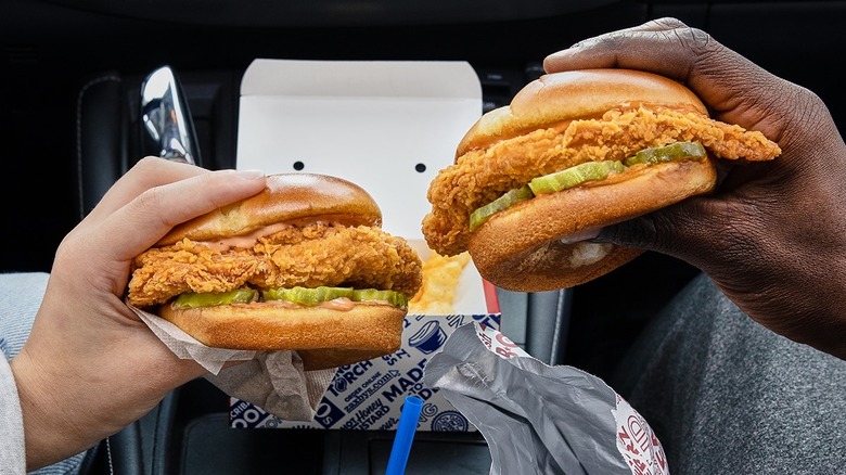 Two hands holding chicken sandwiches