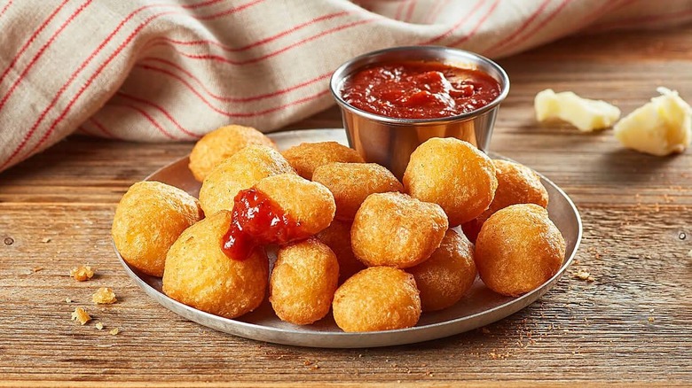 Fried white cheddar bites on a plate with sauce