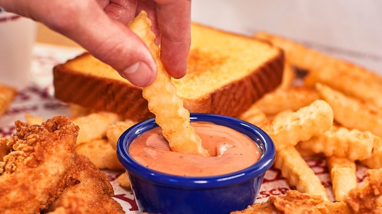 A hand dipping a french fry