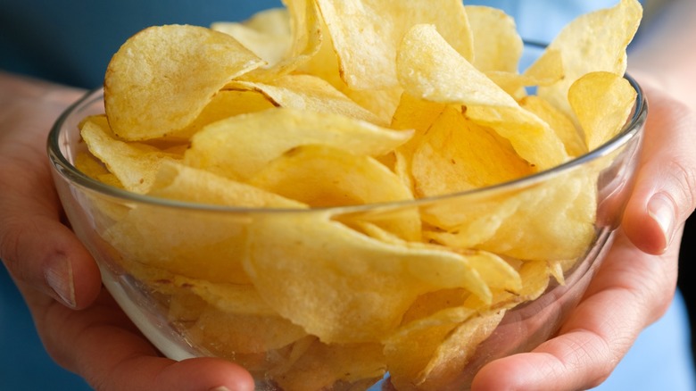 Hands holding a bowl of potato chips