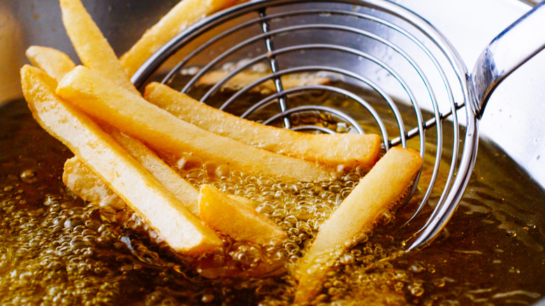 French fries in oil with spoon