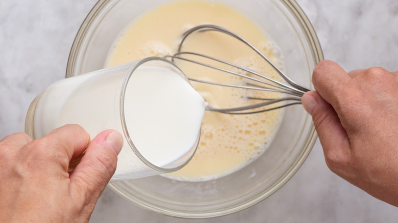 milk added to egg mixture with whisk and bowl