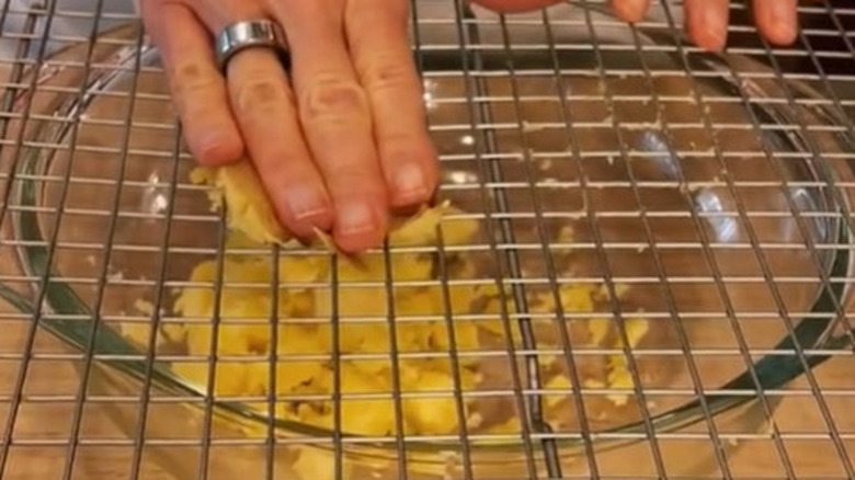 potato on rack with hand and bowl